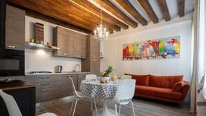 Eine moderne Küche mit Holzbalken, einem Essbereich mit weißen Stühlen und einem farbenfrohen Papageienbild an der Wand.
