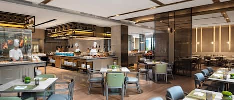 Un restaurante moderno con una barra central, varias mesas para comer y una cocina al fondo.