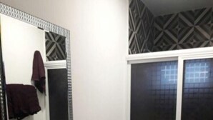 A bathroom with a white sink, a mirror, a toilet, and a shower area. - Condo P (Mazatlán)