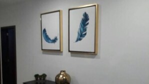 A room with a black console table, two framed artworks, and a gold vase. - Condo P (Mazatlán)
