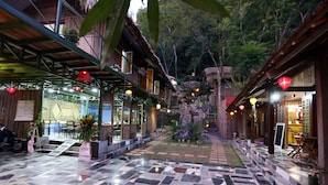 A courtyard with stone flooring, wooden buildings, and hanging lanterns. - Green Hill Hostel & Homestay (Ha Giang 2)
