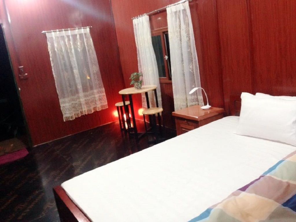 A bedroom with a bed, a small table, a chair, and a desk with a lamp.