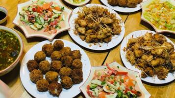 A wooden table with various dishes including fried items, salads, and bowls of sauce.