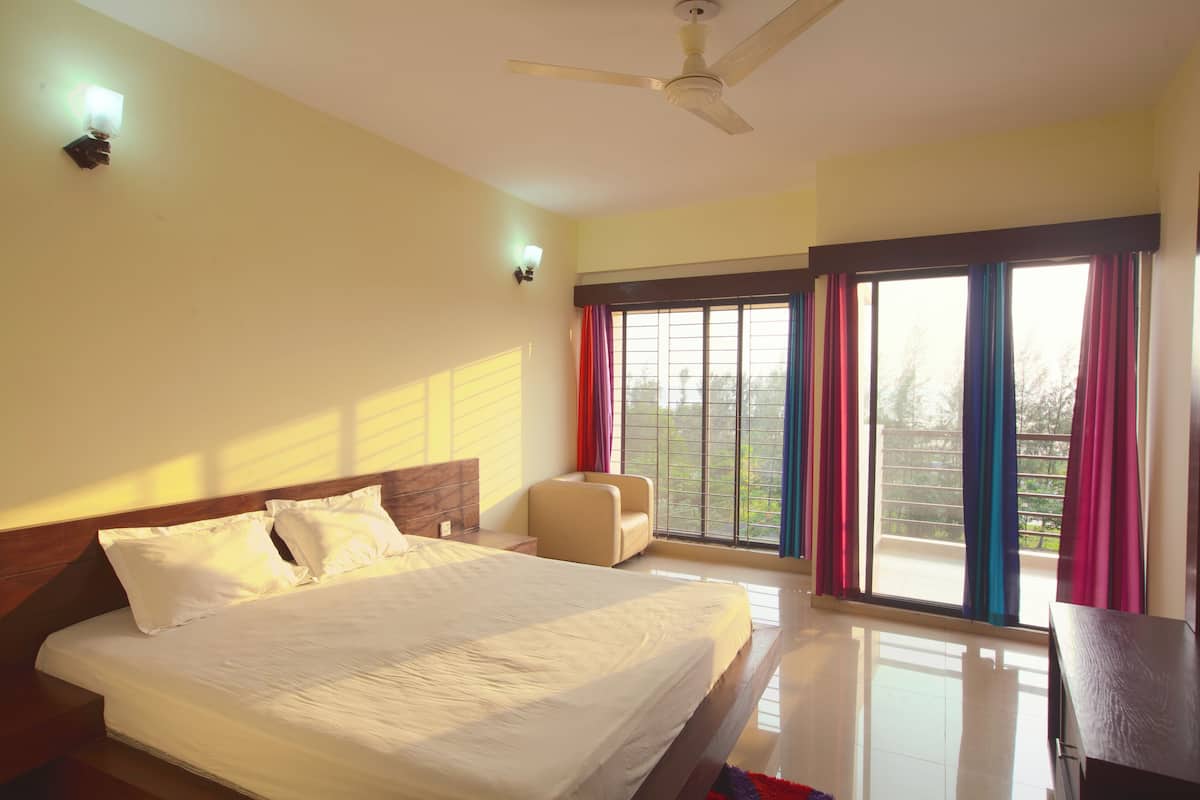 A bedroom with a bed, a ceiling fan, a window with curtains, and a small table.