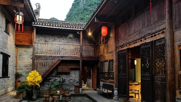 A courtyard with traditional wooden buildings, a stone staircase, and a large planter.