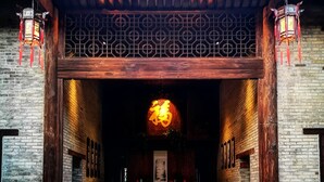 A traditional building entrance with a wooden door, a red carpet, and a table with chairs.