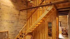 A wooden interior with a staircase, a dining area with chairs, and a table with a plant.