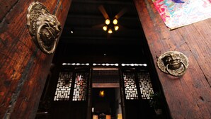 A traditional wooden entrance with decorative metal door handles and a ceiling fan.