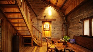 A wooden interior with a staircase, a dining area with a table and chairs, and a bench.