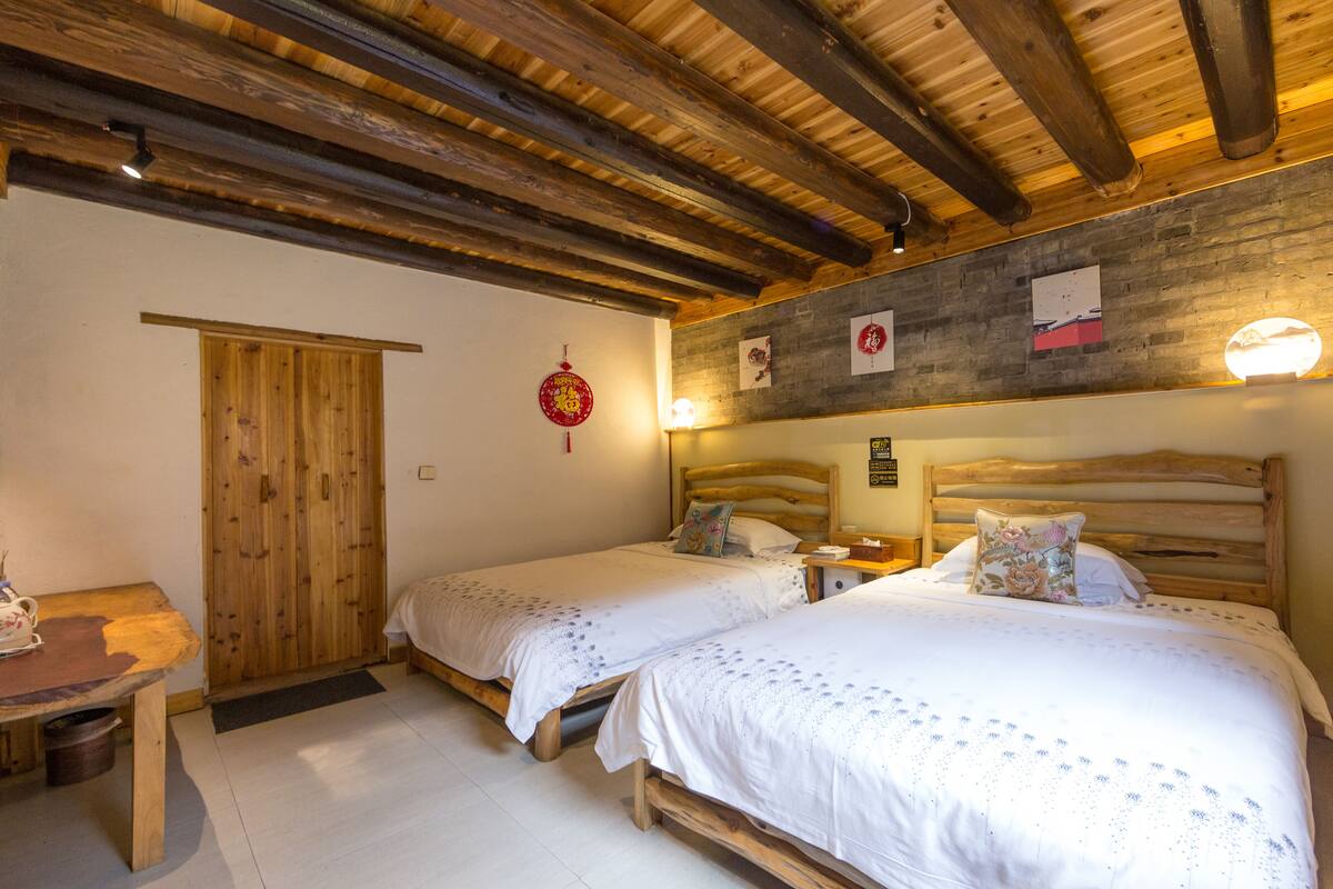 Ein Zimmer mit zwei Holzbetten, einem Holztisch und einem Schrank aus Holz.