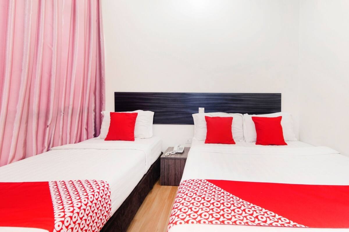 A hotel room with two beds, each with white bedding and red accents, a wooden nightstand, and a telephone.