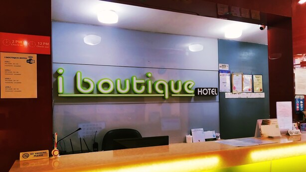 Ein Hotelrezeption mit einem Neon-Schild, auf dem "i boutique HOTEL" steht, und einem Rauchverbot-Schild.