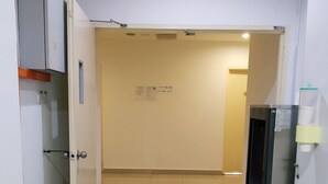Ein Flur mit Kühlschrank, einer Tür und einer Wand mit einem Schild.
