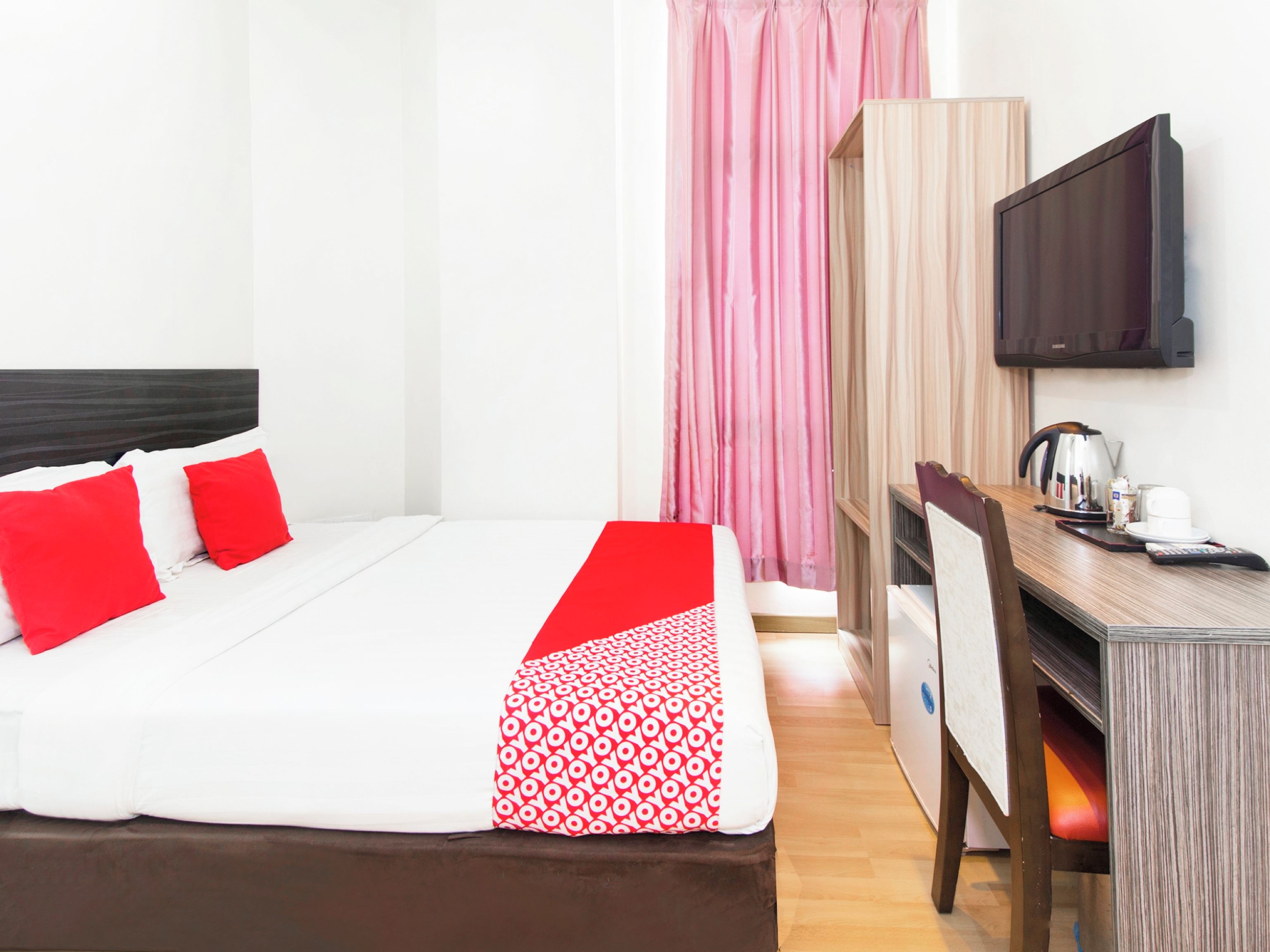 A hotel room with a bed, a desk, a chair, a television, and a wardrobe.