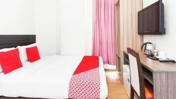 A hotel room with a bed, a desk, a chair, a television, and a wardrobe.