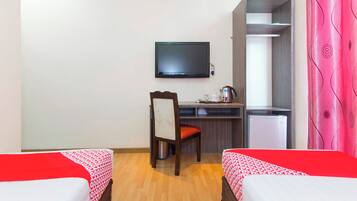 A hotel room with two beds, a desk, a chair, a television, and a wardrobe.