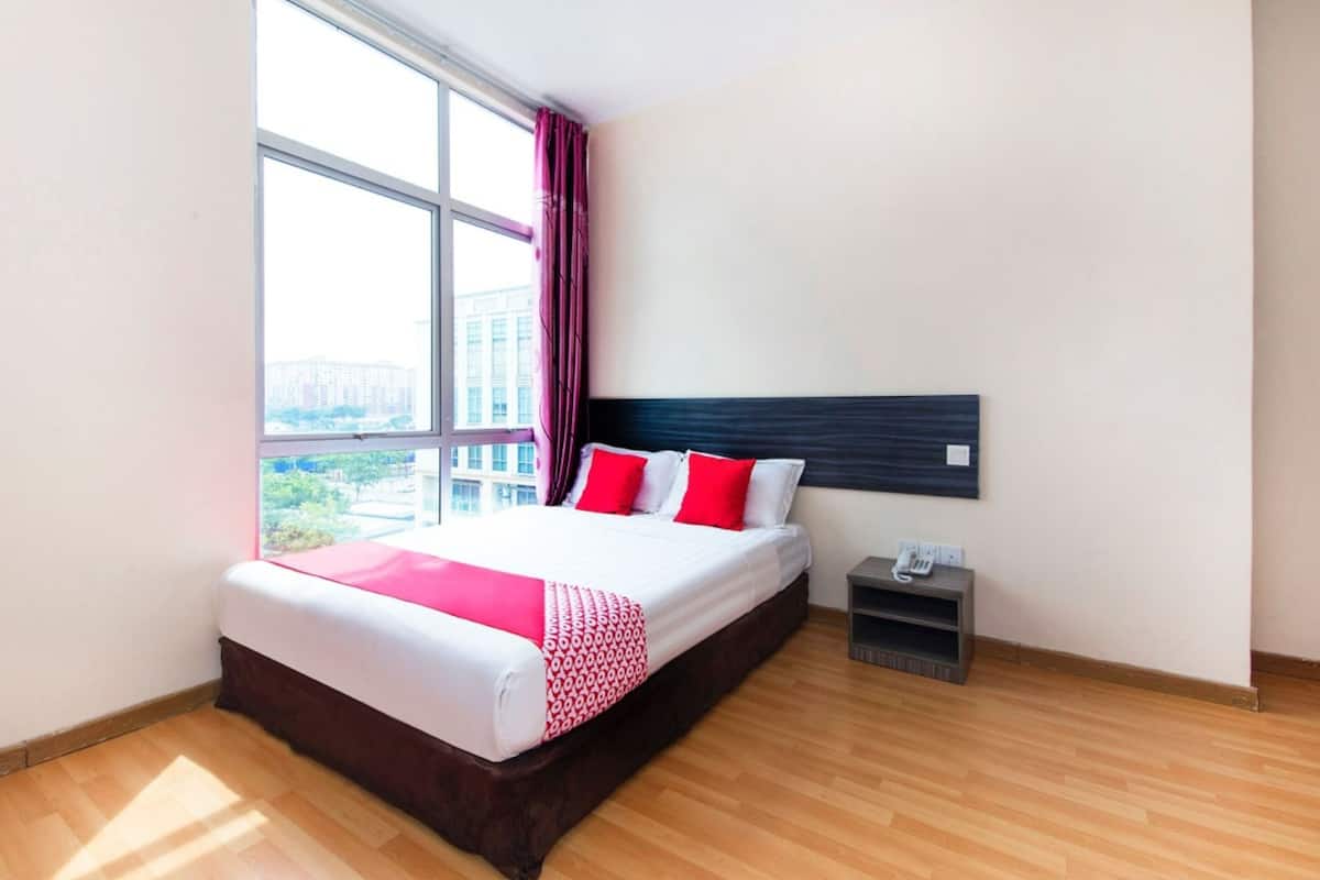 A modern hotel room with a large bed, a nightstand, a window with curtains, and a city view.
