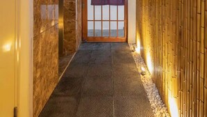A hallway with a tiled floor, a wooden door with a purple curtain, and a bamboo wall. - Azumaya Hotel Linh Lang (Hanoi)