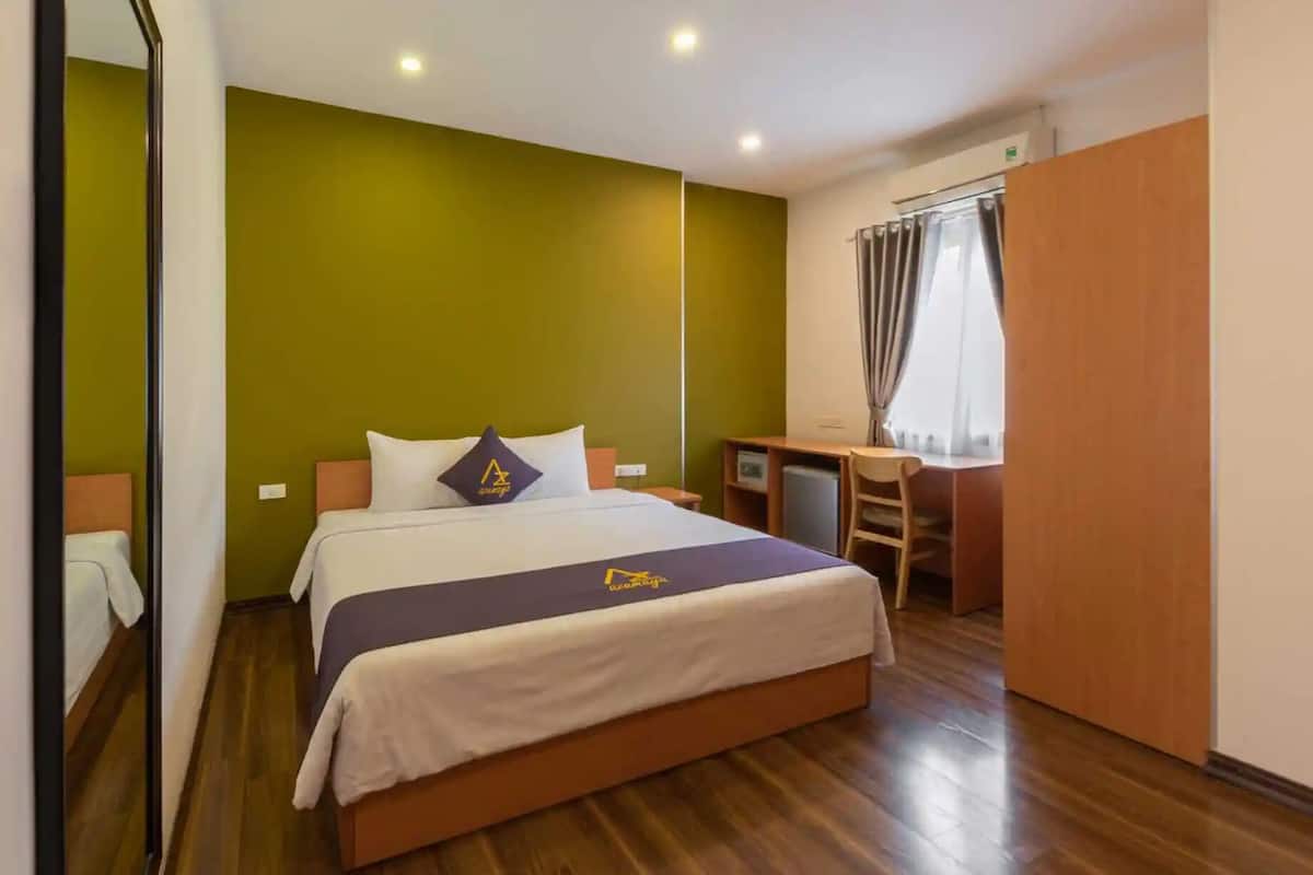 A hotel room with a bed, a desk, and a chair.