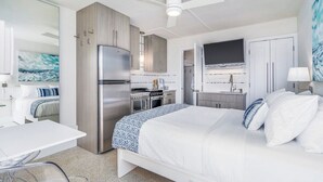 Una habitación de hotel compacta con cama, kitchenette y televisión.