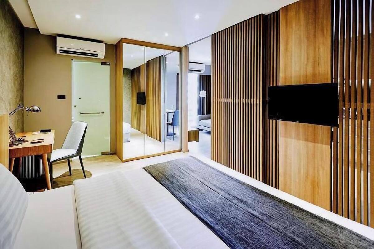 Ein Hotelzimmer mit Bett, Schreibtisch, Stuhl, Fernseher und einer Schiebetür zum Badezimmer.