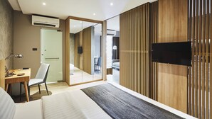 Une chambre d’hôtel moderne dotée d’un grand lit, d’un bureau avec une chaise, d’un téléviseur fixé au mur et d’une porte coulissante donnant accès à la salle de bain.