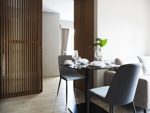 A modern dining area with a table set for two, featuring a plant centerpiece, white plates, and clear glassware. - Aspira Tropical Residence Thong Lor (Bangkok)