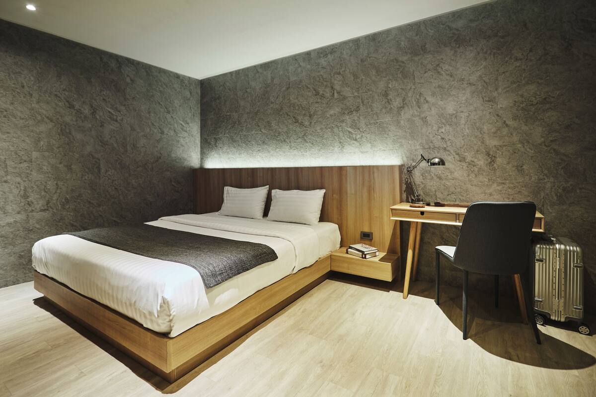 Ein Schlafzimmer mit Bett, Schreibtisch, Stuhl und Koffer.