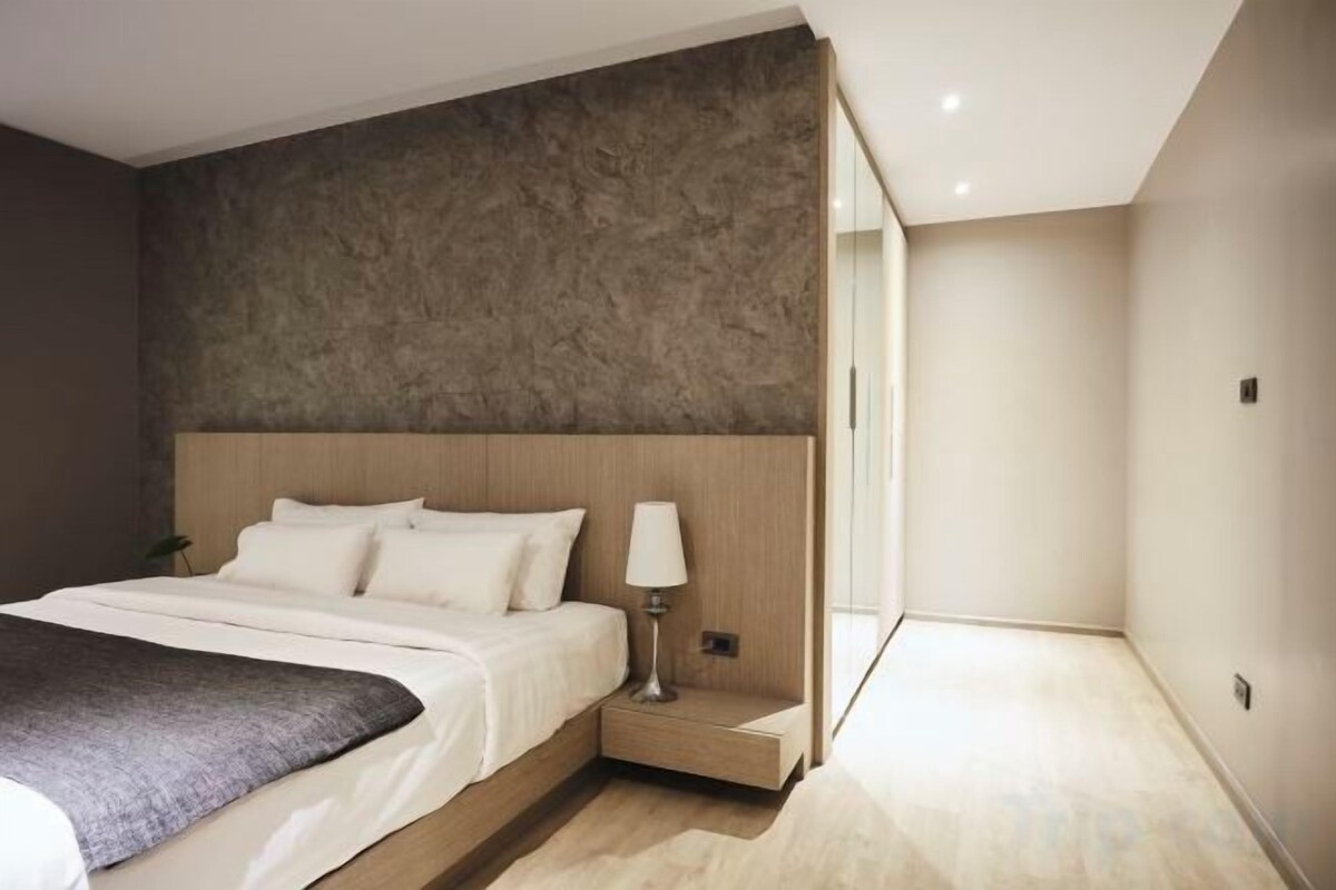 Un dormitorio moderno con una cama grande, una mesita de noche y una lámpara.