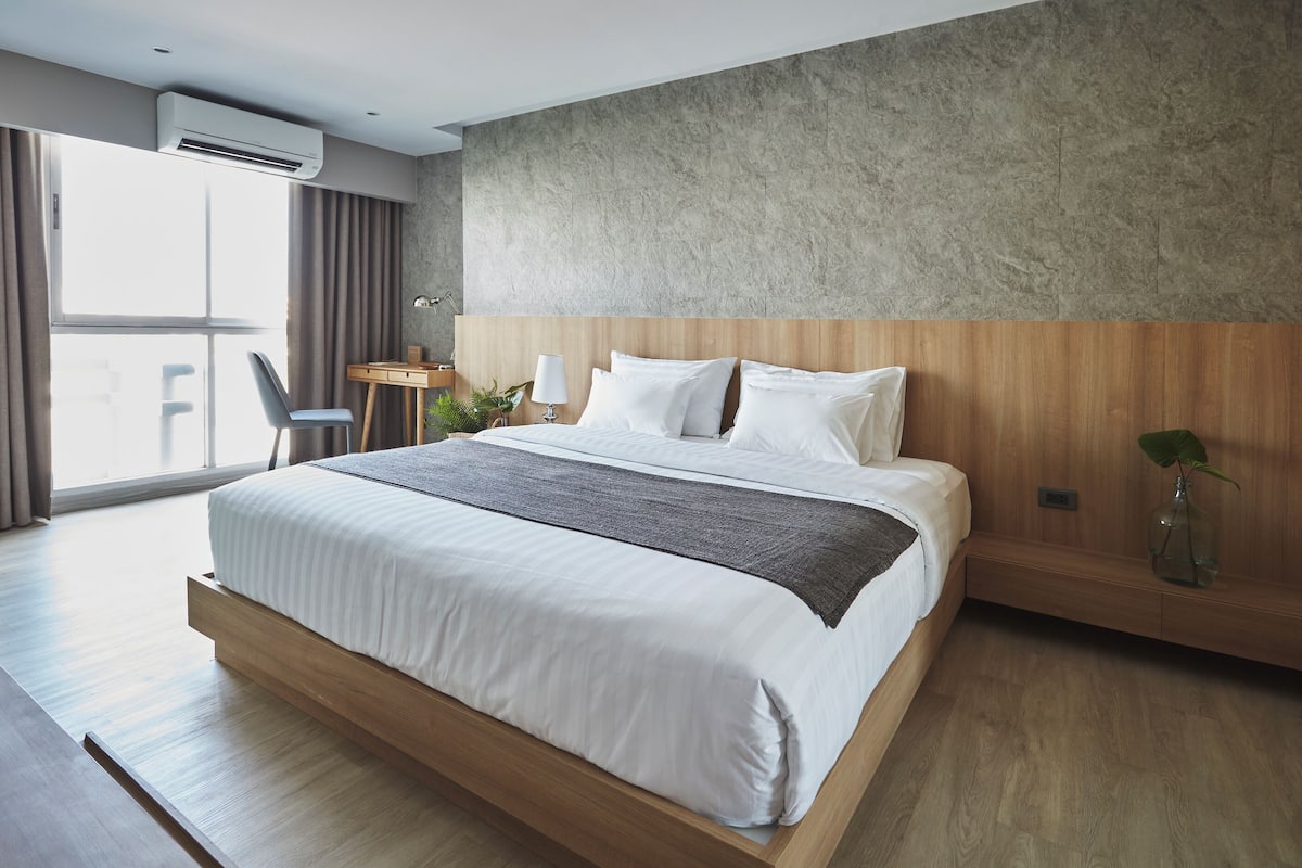 A modern bedroom with a large bed, a desk, and a chair.