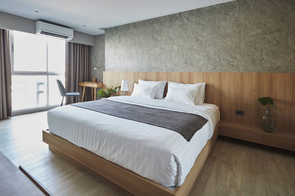 Ein modernes Schlafzimmer mit einem großen Bett, einem Schreibtisch und Blick ins Freie.
