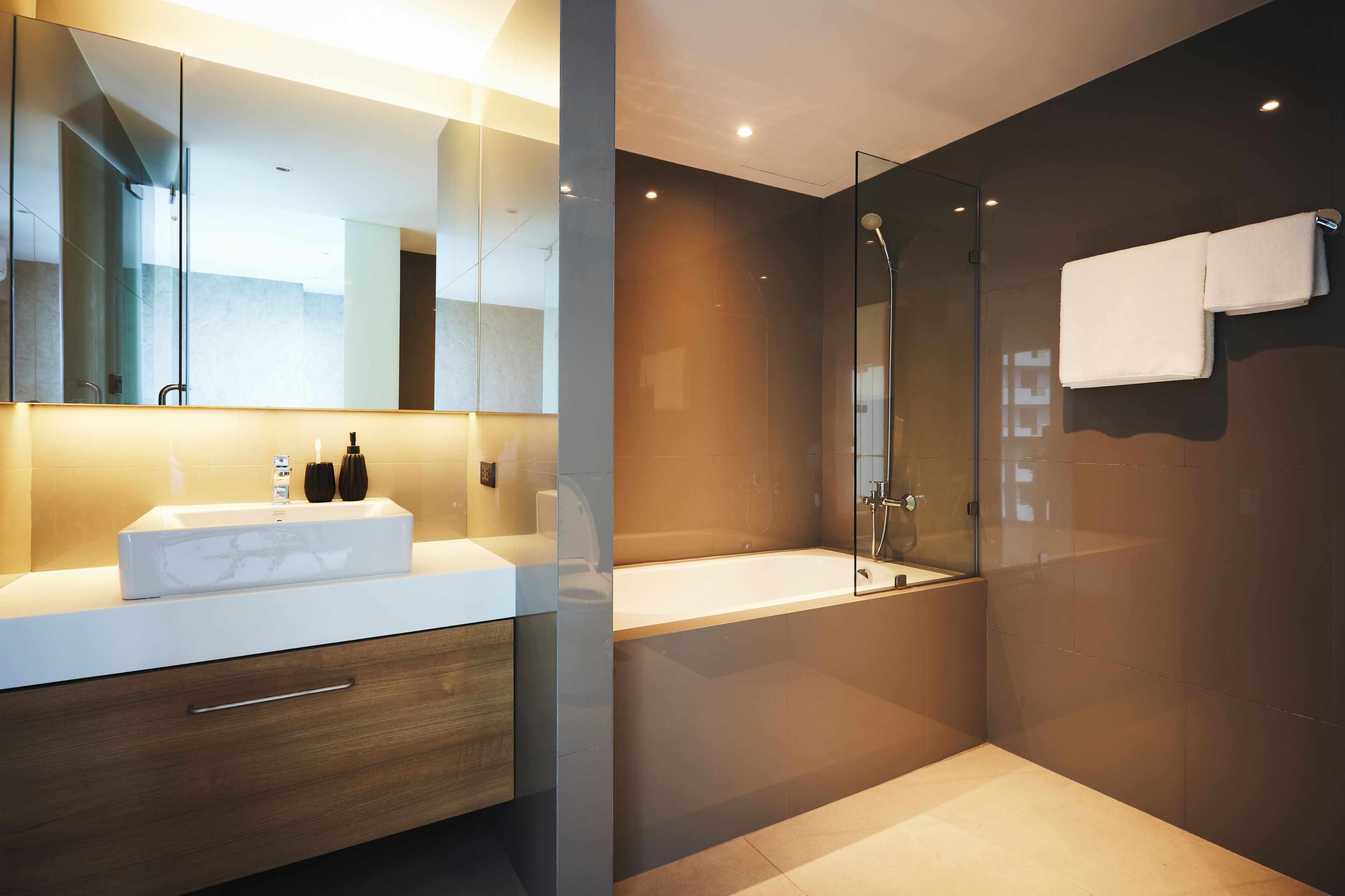 A modern bathroom with a large mirror, a white sink, a glass-enclosed shower, and a towel rack.