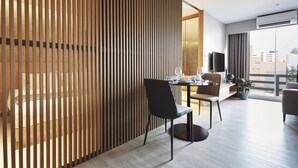 Ein modernes Hotelzimmer mit einer Holzwand, einem Essbereich mit Tisch und Stühlen sowie einem großen Fenster mit Blick auf die Stadt.