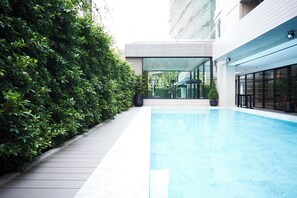Una piscina interior moderna con un suelo de madera y un seto verde.