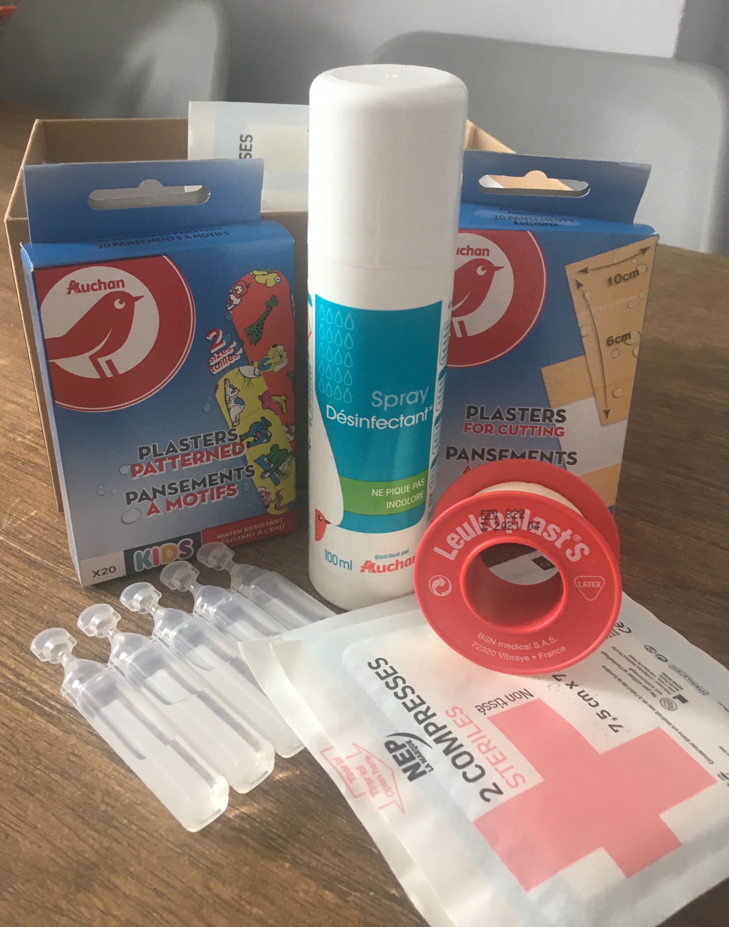 A collection of medical supplies including plasters, a spray disinfectant, and a red latex glove.