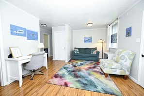 A room with a desk, a sofa, and a patterned rug.