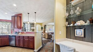 A spacious kitchen with wooden cabinets, a central island, and a dining area with a glass-top table. - Spacious First Floor Condo in Golf Community With Access to Club Amenities! (Cape Charles)