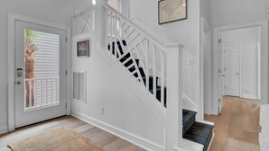 A staircase with white railings and a blue carpet leading to a door with a window. - Award-Winning Resort Amenities | Grand Pavilion 31 by Wild Dunes (Isle of Palms)