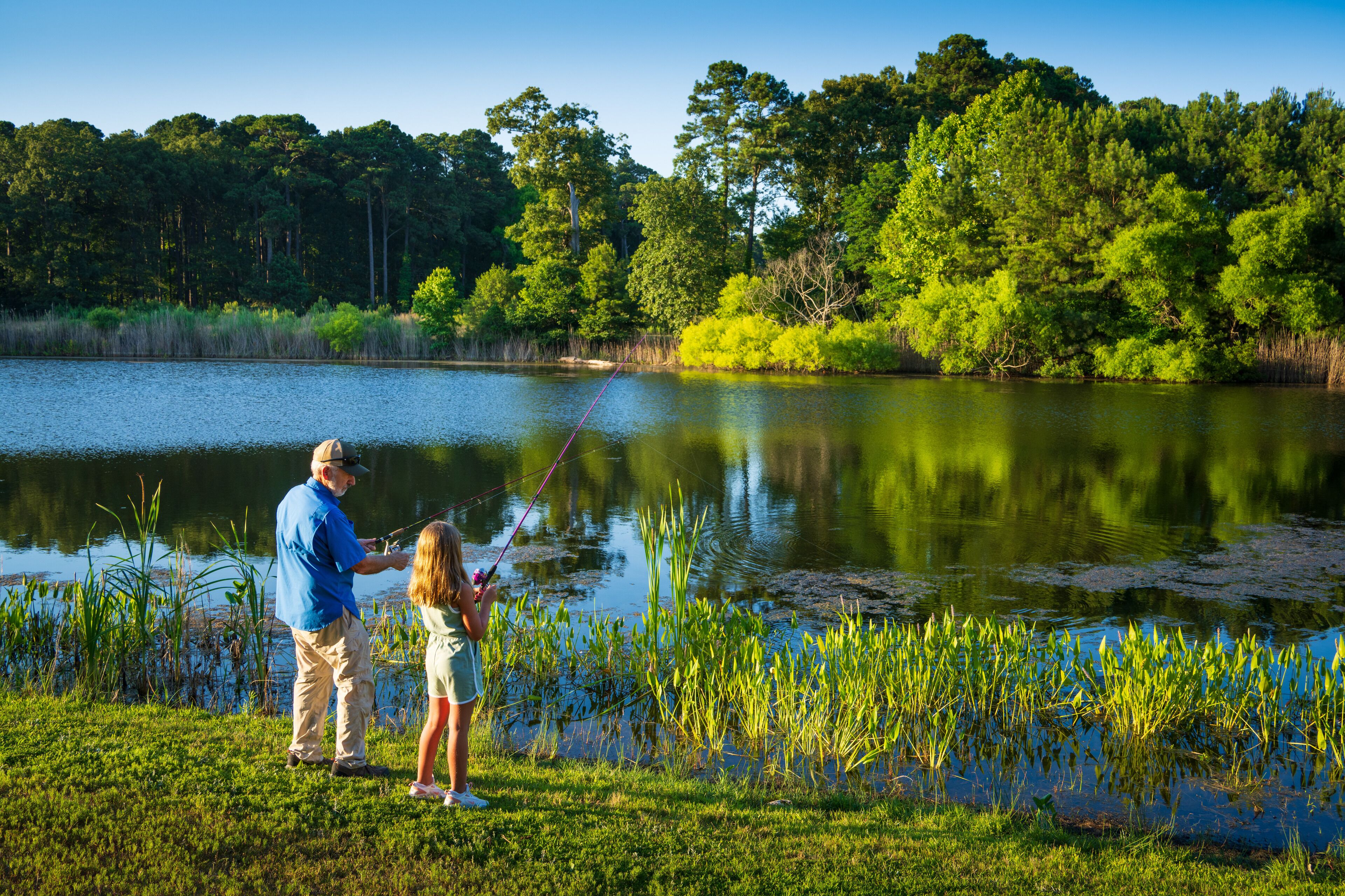 A serene lakeside scene with a man and a child fishing.