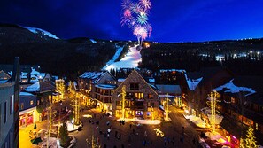 A snow-covered mountain town at night with illuminated buildings and a fireworks display. - Slope Views, Cozy 2 King Beds, Pinball, Short 5 minute Walk to Everything! (Keystone)