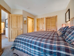 A bedroom with a large bed, wooden doors, and a framed picture on the wall. - Slope Views, Cozy 2 King Beds, Pinball, Short 5 minute Walk to Everything! (Keystone)