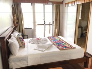 A neatly made bed with white linens, a colorful runner, and a decorative bow. - Tagimoucia House Hotel (Suva)