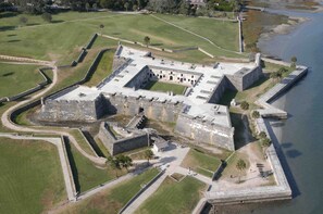 An aerial view of a historic fort with a central courtyard, surrounded by walls and a moat.