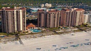 Ein Hotel direkt am Strand mit mehreren Hochhäusern, einem Schwimmbad und einer Strandbucht mit Sonnenschirmen.