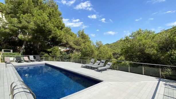 A swimming pool with lounge chairs and a wooden deck.