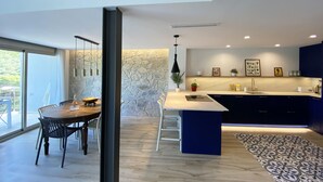A modern kitchen with a stone accent wall, a dining area with a wooden table, and a large island with a sink.