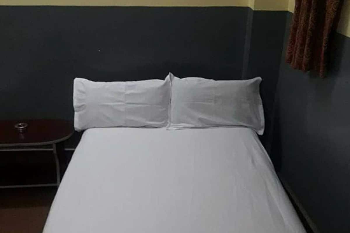 A single bed with white bedding in a room with dark blue and yellow walls.
