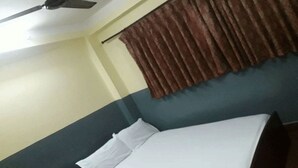 Una habitación con una cama, ventilador de techo y una cortina.