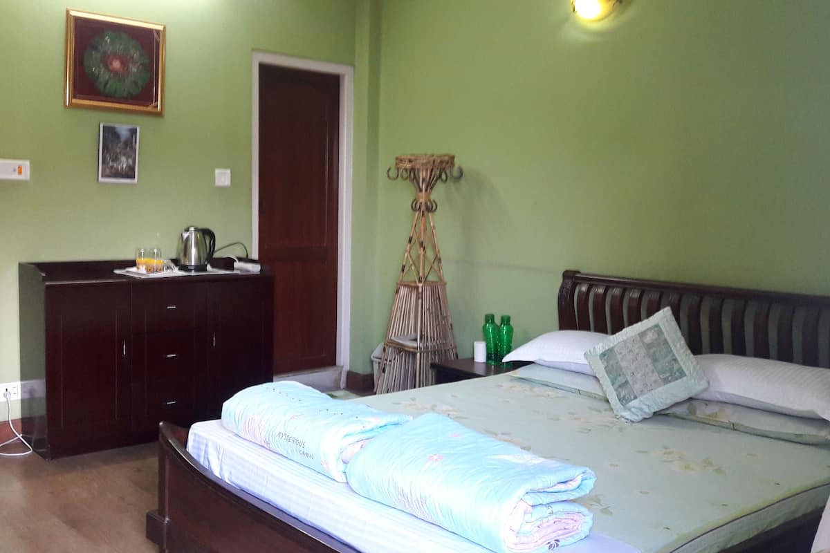 Um quarto com uma cama, cômoda, espelho e porta.