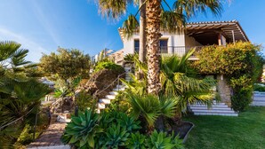 A two-story house with a stone staircase leading to a balcony, surrounded by lush greenery and palm trees. - Luxury Mediterranean Villa, High Standing , Sea Views (Málaga)